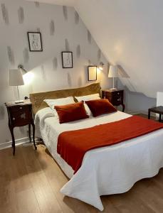 La Balastière في Beaumont-en-Véron: غرفة نوم بسرير كبير عليها شراشف ومخدات حمراء