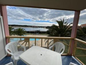 ein Balkon mit Tisch und Stühlen und Blick auf das Wasser in der Unterkunft Appartement confortable 4 pers avec terrasse et accès piscine à Vieux-Boucau - FR-1-379-153 in Vieux-Boucau-les-Bains + 7 Fotos