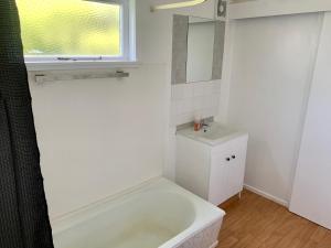 Baño blanco con bañera y lavamanos en RL Two-Bedroom Apartment en Palmerston North