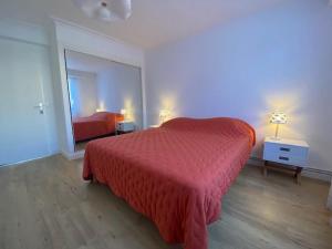 sypialnia z czerwonym łóżkiem i lustrem w obiekcie Appartement rénové 85m2, terrasse, parking, face à plage - FR-1-494-149 w mieście Royan