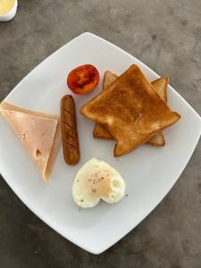 a white plate with pancakes and an egg on it at Ami Mirissa in Mirissa