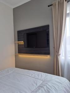 una camera da letto con TV a schermo piatto a parete di Tabebuya Rumah Liburan Keluarga a Bandung