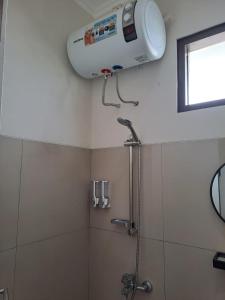 a shower in a bathroom with a fan on the wall at Tabebuya Rumah Liburan Keluarga in Bandung