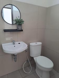 a bathroom with a toilet and a sink and a mirror at Tabebuya Rumah Liburan Keluarga in Bandung