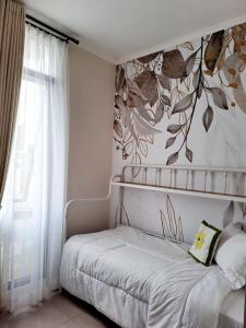 una camera da letto con un letto e un murale floreale sul muro di Tabebuya Rumah Liburan Keluarga a Bandung
