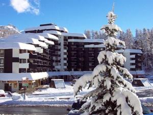 a snow covered pine tree in front of a building at Studio cosy 2 pers à Vars Les Claux, proche remontées mécaniques et centre résidentiel - FR-1-330B-206 in Vars
