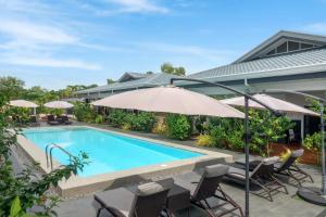 a swimming pool with chairs and an umbrella at Aila Homestay in Bolod