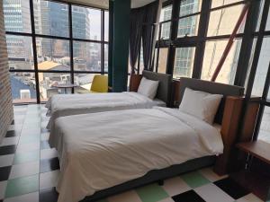 two beds in a hotel room with large windows at LE SEOUL HOTEL in Seoul