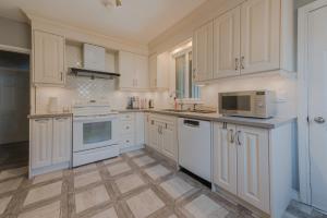 una cocina con armarios blancos y electrodomésticos blancos en Niagara River&Glenview Home-15MinsWalkToFalls en Cataratas del Niágara