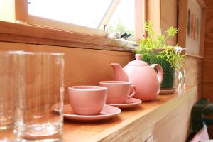 a shelf with cups and vases on a window sill at Escape to a Peaceful Eco Studio in Private Garden in Yapeen