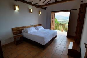 a bedroom with a bed and a door to a balcony at CASA LLANO HIGUERAS in Barichara