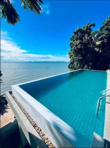 a swimming pool next to a body of water at Eco stay - Luxury pool + Seaview Villa in North Pattaya