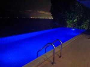 パタヤ・ノースにあるEco stay - Luxury pool + Seaview Villaの青い光が差し込む夜の青いスイミングプール