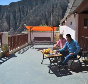 two men sitting at a table on a patio at Hostal Milmahuasi Iruya in Iruya