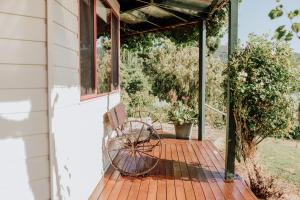 Fleurty's Point Cottage at Franklin South, Huon Valley, Tasmania في Franklin: شرفة خشبية مع مقعد ونافذة