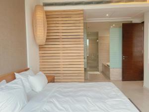 峴港的住宿－Luxury Beach Resort Apartments & Villas，卧室配有白色的床和步入式淋浴间。