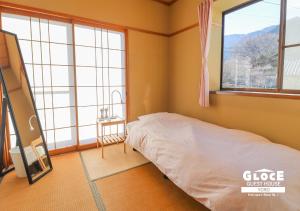 a bedroom with a bed in a room with windows at GLOCE 養老 西小倉ハウス 1 l 広々とした一軒家を貸切 l 無料駐車場有 l 中長期向け in Yoro