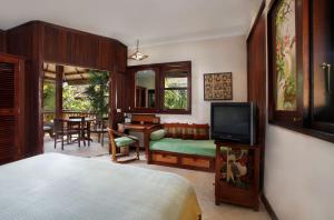 a bedroom with a bed and a television and a table at Pondok Agung Bed & Breakfast in Nusa Dua