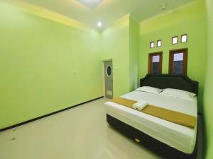 a bedroom with a large bed with green walls at Tentrem Homestay by FHStay in Sleman