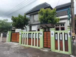 a house with a green fence in front of it at Tentrem Homestay by FHStay in Sleman