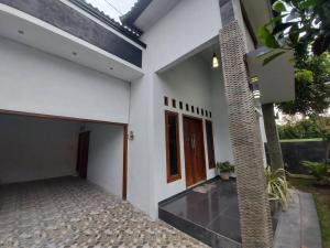 a white house with a door and a courtyard at Tentrem Homestay by FHStay in Sleman