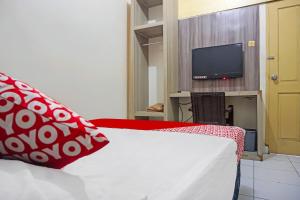 een slaapkamer met een bed en een tv op de achtergrond bij OYO 1935 Hotel Diamond Inn Makassar in Makassar