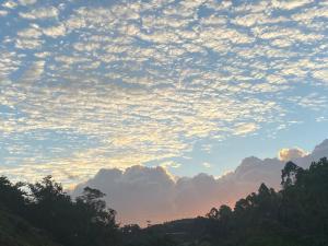 um céu nublado ao pôr-do-sol com árvores em primeiro plano em Chalé da Estância em Santa Teresa ES em alto São Lourenço Proximo ao circuito Caravaggio 5 km em Santa Teresa