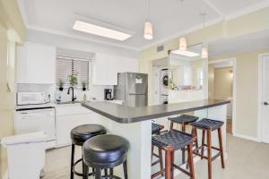 a kitchen with white cabinets and bar stools at Beachside Surf Haven in Jacksonville Beach