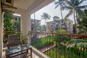 d'un balcon avec un banc, des palmiers et des bâtiments. dans l'établissement Amazing Pool View Candolim Goa 2BHK Apartment, à Candolim