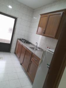 a small kitchen with a sink and a refrigerator at Al Karawan Hotel Apartments in Amman