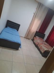 a bedroom with two beds and a tile floor at Al Karawan Hotel Apartments in Amman