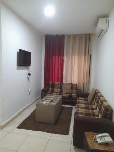 a living room with two couches and a tv at Al Karawan Hotel Apartments in Amman
