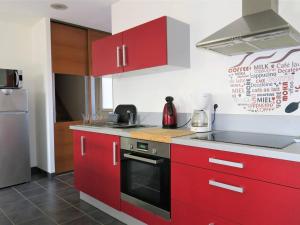 eine Küche mit roten Schränken und einem Herd mit Backofen in der Unterkunft Maison Trégastel, 3 pièces, 3 personnes - FR-1-368-190 in Trégastel