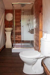 a bathroom with a toilet and a glass shower at Glamping tent in Pelaga Eco Park in Patjung