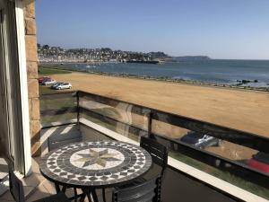 einen Tisch und Stühle auf einem Balkon mit Blick auf den Strand in der Unterkunft Appartement Perros-Guirec, 2 pièces, 4 personnes - FR-1-368-293 in Perros-Guirec