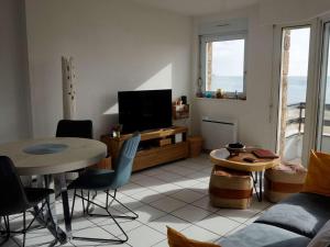 ein Wohnzimmer mit einem TV, einem Tisch und Stühlen in der Unterkunft Appartement Perros-Guirec, 2 pièces, 4 personnes - FR-1-368-293 in Perros-Guirec