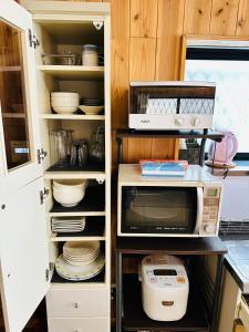eine Küche mit einer offenen Pantryküche mit einer Mikrowelle in der Unterkunft Biwako AshiのMori 温泉付き in Takashima