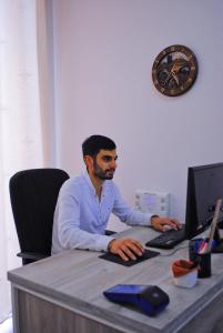 a man sitting at a desk with a computer at Hotel Erebuni Plaza in Yerevan