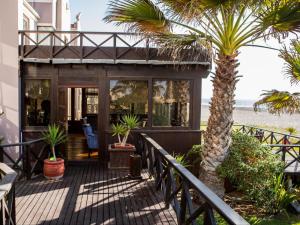 ein Haus am Strand mit einer Palme in der Unterkunft Burning Shore Hotel in Langstrand