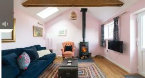 a living room with a blue couch and a fireplace at Fletchers Cottage in Honiton