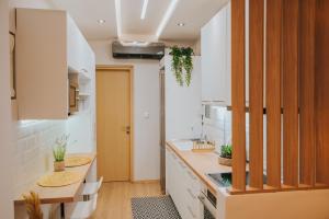 une cuisine avec des placards blancs et une table en bois dans l'établissement new cozy by the sea apartment, à Thessalonique