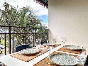 a table with plates and wine glasses on a balcony at Arbre de Jade, 49 m² joli T3 à la Bretagne in Sainte-Clotilde