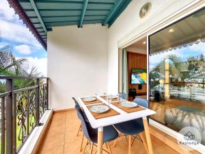 a dining room with a table and chairs on a balcony at Arbre de Jade, 49 m² joli T3 à la Bretagne in Sainte-Clotilde