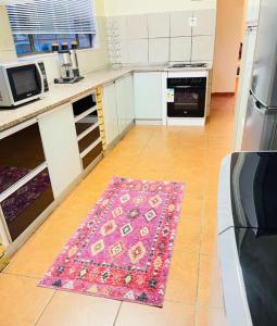 uma cozinha com um tapete rosa no chão em 25 Swallow Yellowood em Durban