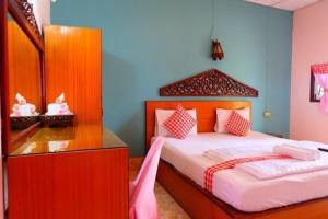 een slaapkamer met een groot bed en een spiegel bij โรงแรม พี รีสอร์ท in Kamphaeng Phet