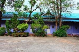 un bâtiment violet avec des arbres devant lui dans l'établissement โรงแรม พี รีสอร์ท, à Kamphaeng Phet