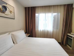 a bedroom with a large white bed with a window at Link Hotel Singapore in Singapore