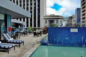 una piscina con sillas y mesas en una ciudad en Cresta Grande Cape Town, en Ciudad del Cabo