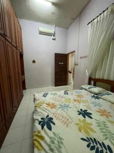 a bedroom with a bed with a floral bedspread at MIA FAMILIA HOMESTAY in Cukai