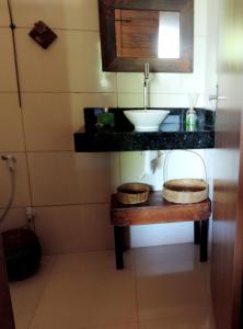 a bathroom with a sink and a table with a mirror at Chalé do Beco - Nova Caraíva in Porto Seguro